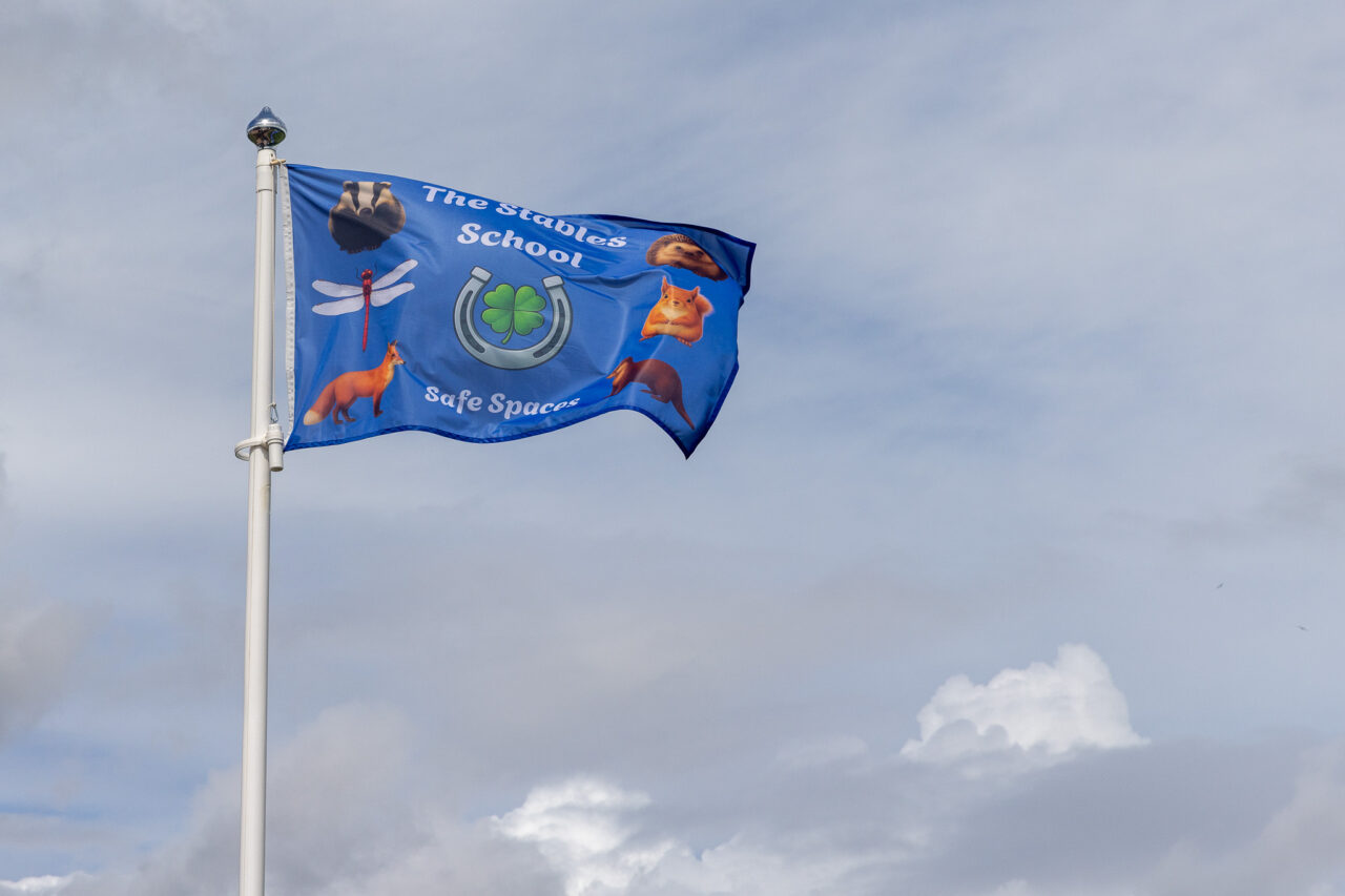 The Stables School flag flying against the sky